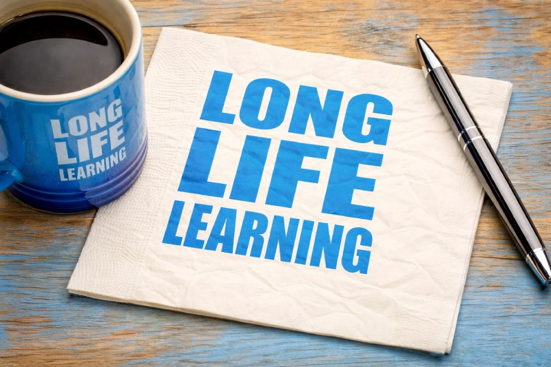 grafika z kubkiem kawy i serwetką na ktorej jest hasło long life learning